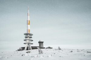 Capture of the snowy Brocken transmitter tower in Harz, Germany, against a clear winter sky.