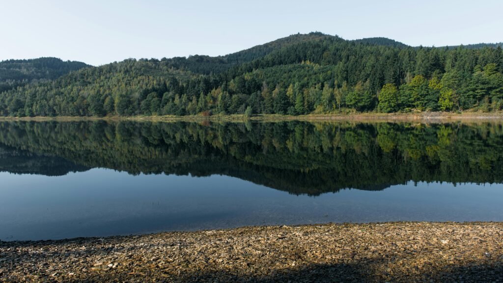 pexels-photo-31231389-31231389 Tranquil reflection of forested hills in a calm lake in Langelsheim, Germany. A perfect escape to nature.