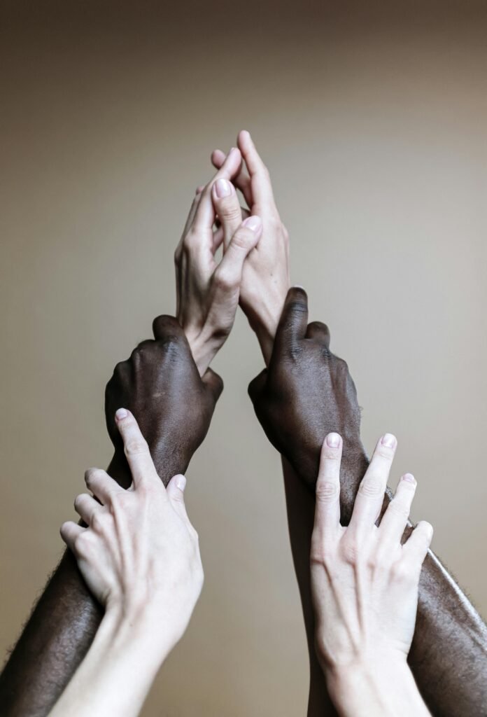 Todos somos UNO Multiple hands of different ethnicities reaching up, symbolizing unity and togetherness.