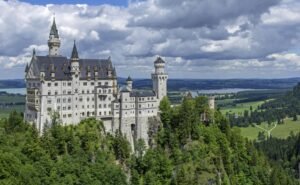 Stunning view of Neuschwanstein Castle surrounded by lush green forests and clouds.